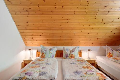 two beds in a room with a wooden ceiling at Hugenhof in Kirchzarten