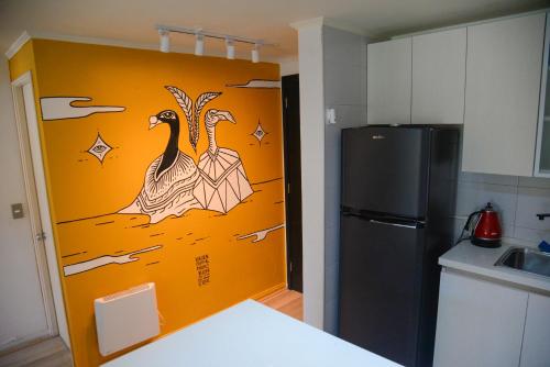 a kitchen with a wall with a painting of two peacocks at Exclusivo Departamento in Concepción