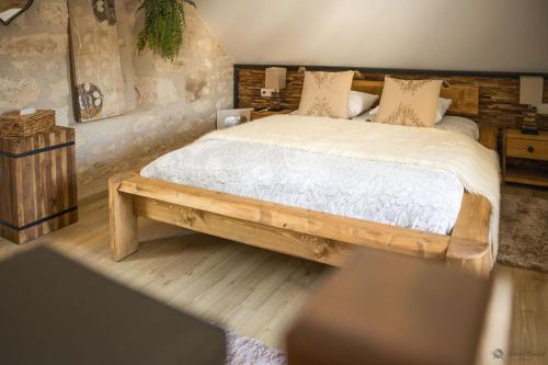 a bedroom with a wooden bed with white sheets and pillows at La Ferme de Labbeville in Labbeville