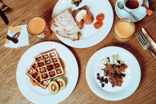 a table with white plates of breakfast foods at Max Brown Hotel 7th District, part of Sircle Collection in Vienna