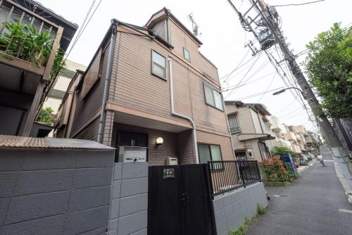 a brown house with a black gate on a street at 楽逸 中井 104t in Tokyo