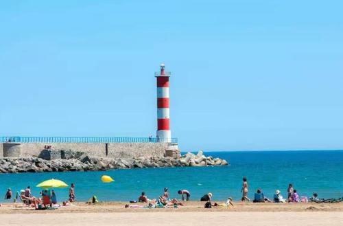 un grupo de personas en una playa con un faro en Tiny house Port la Nouvelle, en Port-la-Nouvelle