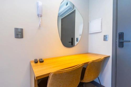 a table with chairs and a mirror on a wall at Vibe Curitiba by Housi, próximo à Ligga Arena e Praça do Japão in Curitiba