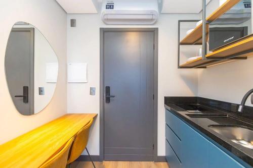 a kitchen with a sink and a mirror at Vibe Curitiba by Housi, próximo à Ligga Arena e Praça do Japão in Curitiba