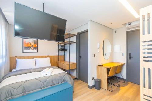 a bedroom with a bed with a flat screen tv at Vibe Curitiba by Housi, próximo à Ligga Arena e Praça do Japão in Curitiba