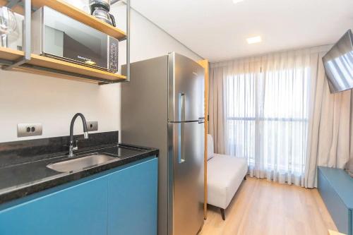 a kitchen with a stainless steel refrigerator next to a window at Vibe Curitiba by Housi, próximo à Ligga Arena e Praça do Japão in Curitiba
