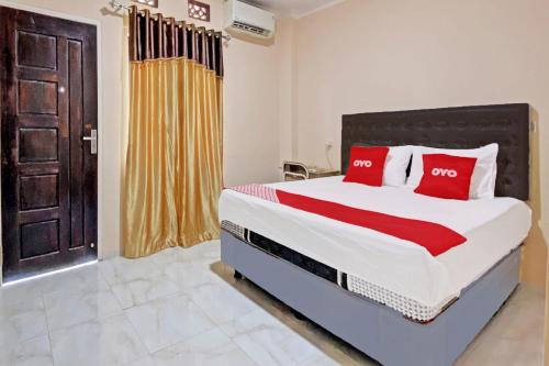 a bedroom with a large bed with red pillows at Hotel O Kos 21 in Kupang