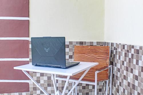 a laptop sitting on a white table next to a chair at Hotel O Kos 21 in Kupang