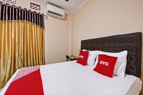 a bedroom with a bed with red and white pillows at Hotel O Kos 21 in Kupang