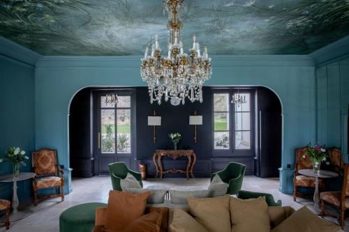 a living room with blue walls and a chandelier at Les Hayes en Sologne in Fontaines-en-Sologne