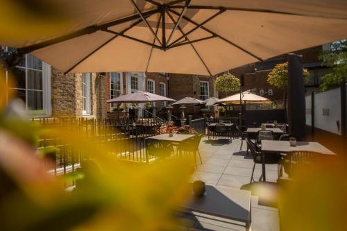 an outdoor patio with tables and chairs and umbrellas at Richmond Hill Hotel in Richmond upon Thames