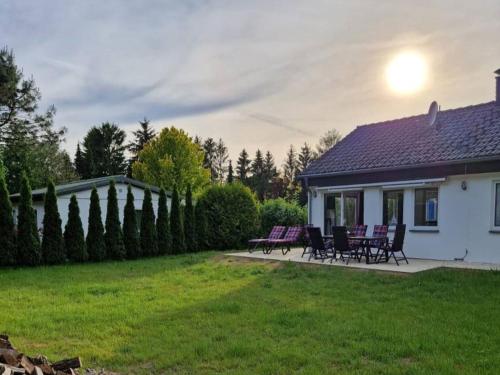 a white house with purple chairs and a yard at Ferienhaus am See 19 in Zehdenick