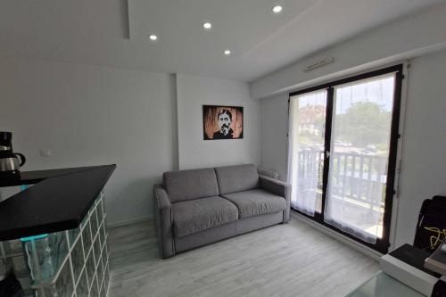 un salon avec un canapé et une grande fenêtre dans l'établissement T2 with balcony close to the beach of Cabourg, à Cabourg