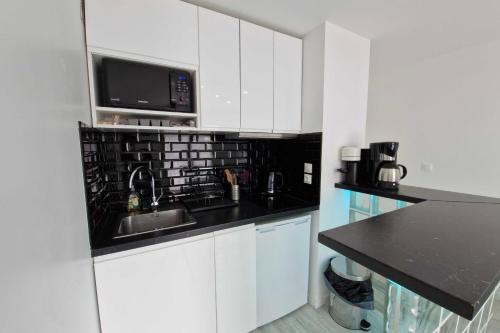 une cuisine blanche avec un évier et un micro-ondes dans l'établissement T2 with balcony close to the beach of Cabourg, à Cabourg