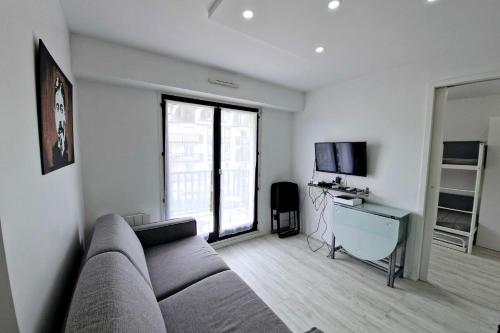 un salon avec un canapé et une télévision dans l'établissement T2 with balcony close to the beach of Cabourg, à Cabourg