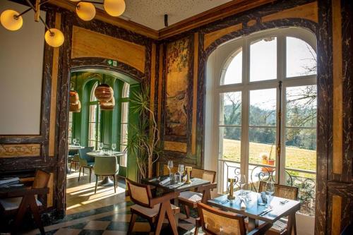 a dining room with tables and a large window at Le Petit Château Peltzer in Verviers