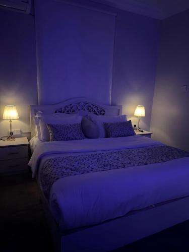 a purple bedroom with a large bed with two lamps at مسكن كازان in Abha