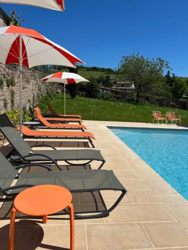 a group of chairs and umbrellas next to a swimming pool at Chambres d'hôtes Vers la Croix in Leynes