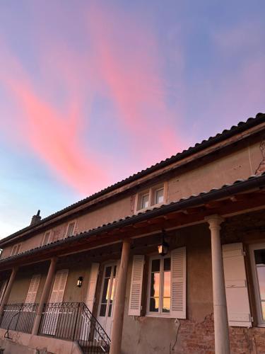 a house with columns and a cloudy sky at Chambres d'hôtes Vers la Croix in Leynes