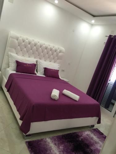 a bedroom with a large bed with purple sheets and pillows at Queen Kodre Apartments in Ulcinj