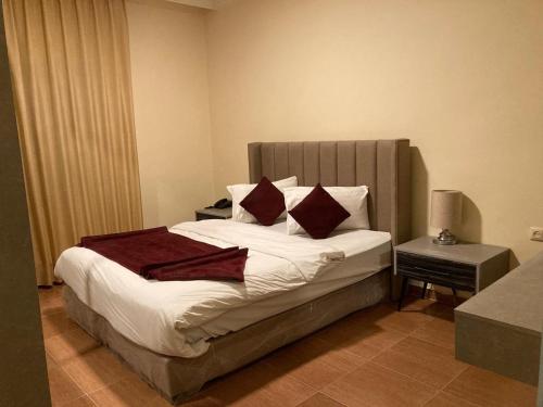 a bedroom with a large bed with red pillows at Uptown Hotel Apartment in Amman
