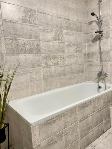 a white bath tub in a bathroom with tiles at Центр поруч озеро та парк 4 квартира подобово in Ternopilʼ