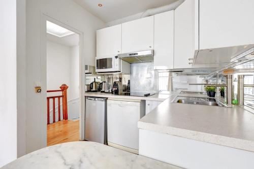 une cuisine avec des armoires blanches et des appareils en acier inoxydable dans l'établissement Duplex cozy a Proximite de la Tour Eiffel with AC, à Paris