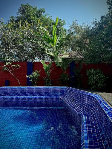 a blue tile swimming pool in front of a fence at GOAROUND - Honeydew Suites at Vagator by Goaround Homes in Vagator