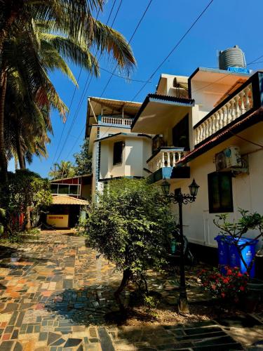 a house with a palm tree in front of it at GOAROUND - Honeydew Suites at Vagator by Goaround Homes in Vagator