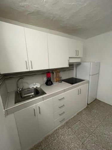 a kitchen with white cabinets and a sink and a refrigerator at Casa ADOLFO in Almáciga