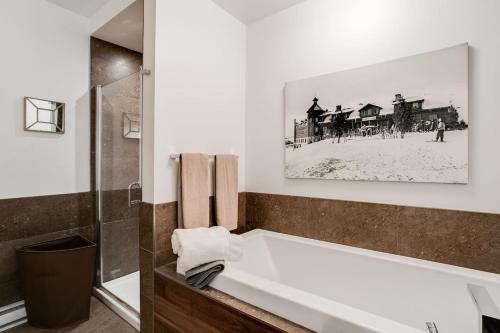 a bathroom with a bath tub with a picture on the wall at Condo Luxueux au pied du Mont in Saint-Sauveur-des-Monts