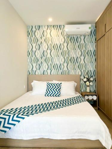 a bedroom with a bed with a blue and white patterned wall at Monica Homestay - Căn hộ The Song Vũng Tàu in Vung Tau