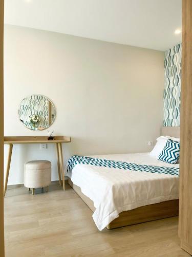 a bedroom with a bed and a table with a mirror at Monica Homestay - Căn hộ The Song Vũng Tàu in Vung Tau