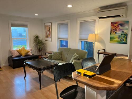 a living room with a couch and a table with a laptop at East Side Blue Bonnet Cottage in Austin