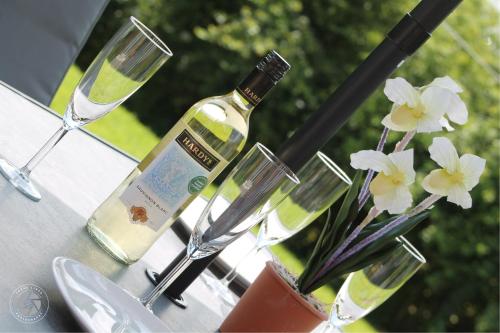 a bottle of wine and glasses on a table with flowers at Home with HotTub near AltonTowers & Waterworld sot in Stoke on Trent