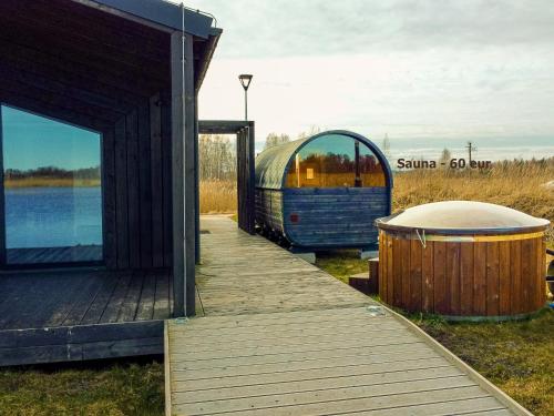 a building with a wooden walkway next to a tub at Lielpīles in Radziņciems