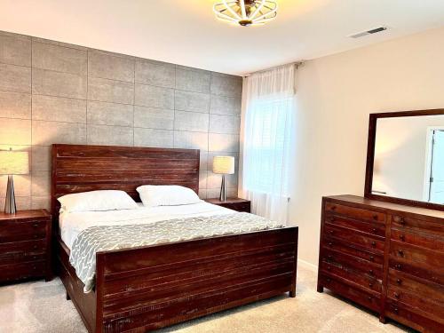 a bedroom with a large wooden bed and a mirror at The Villas The One Villa by RDU Airport with Indoor Heated Pool and Gym in Durham