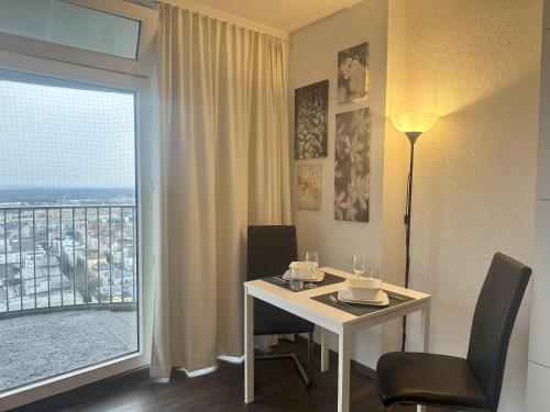 Cette chambre d'hôtel dispose d'une table et d'une grande fenêtre. dans l'établissement Tower Suite Hotelturm Augsburg, à Augsbourg