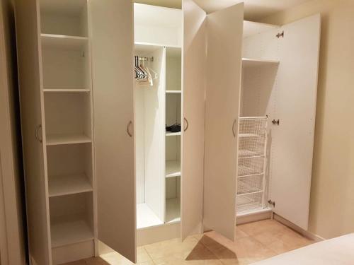 a walk in closet with white walls and shelves at Cosy, modern apartment near the city center in Senja