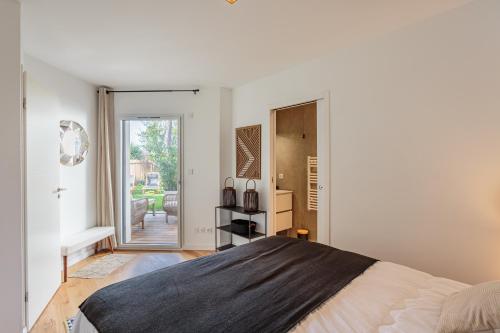 - une chambre avec un lit et une porte donnant sur une terrasse dans l'établissement KARUKERA Bel appartement avec jardin au cœur de Chiberta, à Anglet