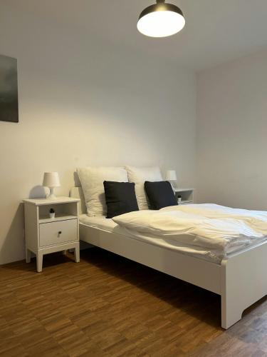 ein weißes Bett in einem Zimmer mit einem Nachttisch in der Unterkunft Modernes Business-Apartment, 2 Zimmer, zentrale Lage in Hamburg in Hamburg