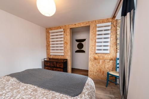 a bedroom with a bed and two windows at Gite du Canal in Josselin
