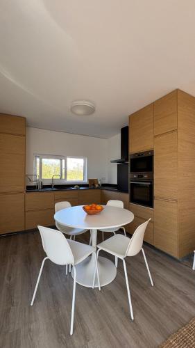 a kitchen with a white table and white chairs at LAZY HIKERS by Nature Bliss in São Luis