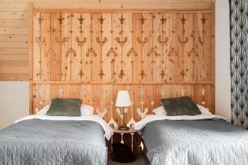 two beds in a room with a wooden wall at Domki Szczyt Beztroski - Balia & Sauna in Nowy Targ