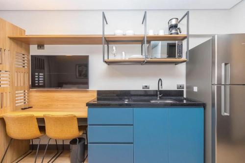 a kitchen with blue cabinets and a sink and a microwave at Vibe Curitiba by Housi, próximo à Ligga Arena e Praça do Japão in Curitiba