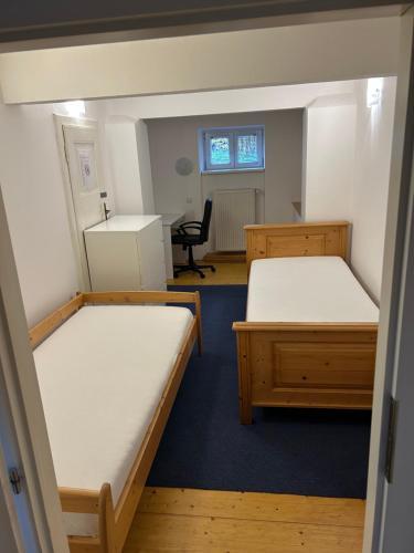 two beds in a room with a desk and a chair at Apartmány u Kubíků in Hradec Králové