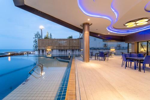 a swimming pool with tables and chairs on a building at Rodina Beach Hotel in Jomtien Beach