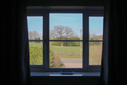 a window with a view of a field seen through it at Home with HotTub near AltonTowers & Waterworld sot in Stoke on Trent
