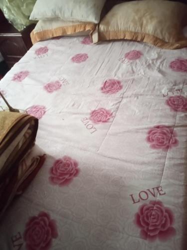 a bed with pink roses on it with the words love at Chez l habitant mayorka in Sefrou