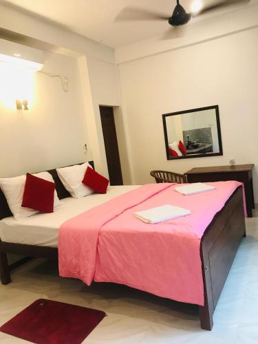 a bedroom with a large bed with a pink blanket at BLUE WHALES HOTEL in Hikkaduwa